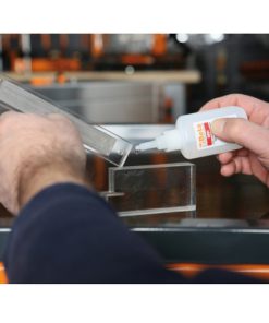 foto van iemand die contactlijm van beta gebruik bij het verlijmen van doorzichtig kunststoffen delen